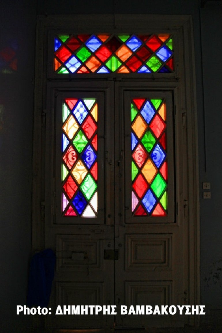 Η πόρτα της κυρίας εισόδου από την εσωτερική της πλευρά, με το υπέροχα πολύχρωμα τζάμια που διατηρούνται έως σήμερα