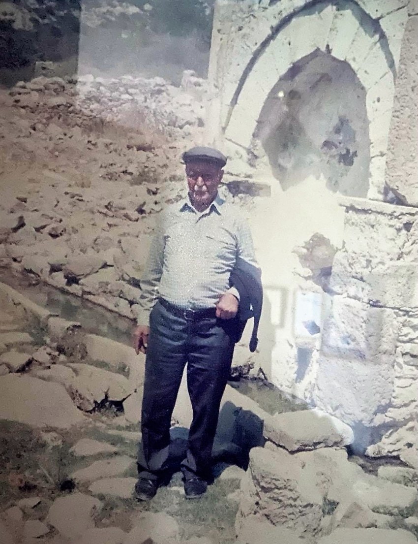 Στη φωτογραφία, φαίνεται ο Γιώργος Χατζημανώλης σε προσκυνηματική επίσκεψη στο ερειπωμένο Μελί, μπροστά στην Κρήνη του Χέλιου.